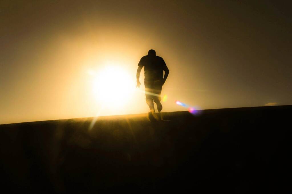 man running up a hill barefoot.